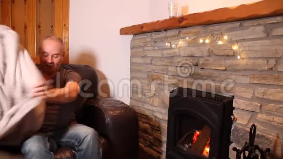 中年人坐在炽热的壁炉旁沉思地看着炉火想着冬天的放松视频的预览图
