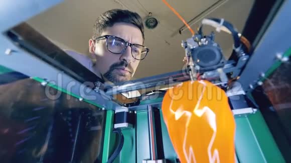 3D打印机从塑料中打印物体男工程师正在看一个3D打印机里面的花瓶视频的预览图