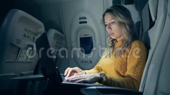 飞机舱半暗一个女人在笔记本电脑上打字视频的预览图