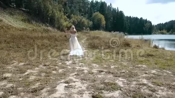 女孩穿过树林把一件白色的裙子拉到地上视频的预览图