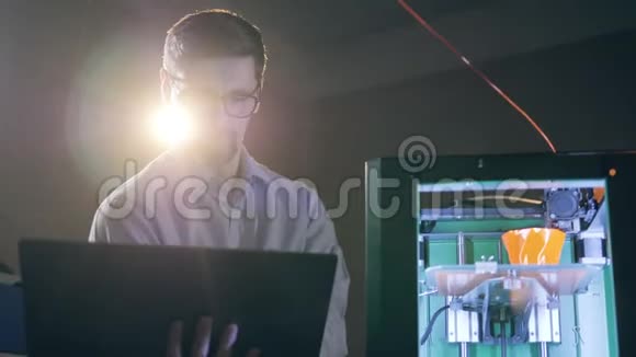 一名携带笔记本电脑的技术人员正在检查一个正在工作的3D打印机视频的预览图