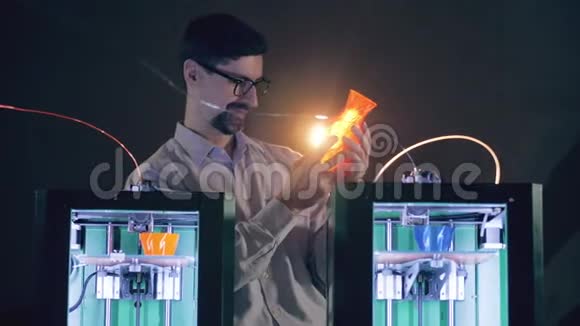 男性专家正在观察3D打印机旁边的花瓶视频的预览图