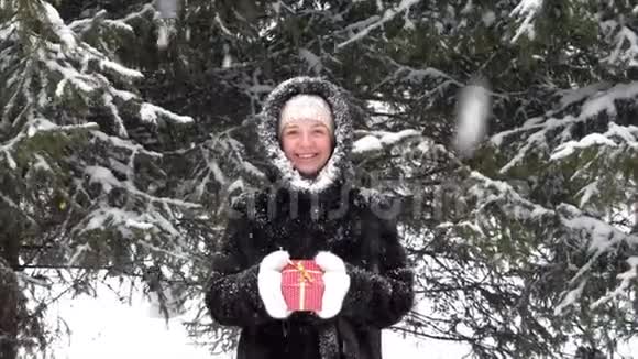 手拿红色圣诞礼盒的冬装快乐微笑的女人视频的预览图