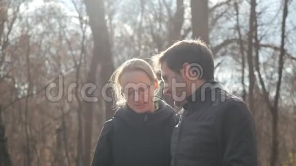 幸福的微笑妻子和丈夫在秋天站在舒适的城市公园里的溜冰鞋上交流和微笑男子视频的预览图