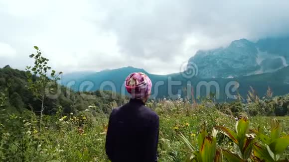 一位到山边欣赏美丽景色的女游客的近而远的镜头视频的预览图