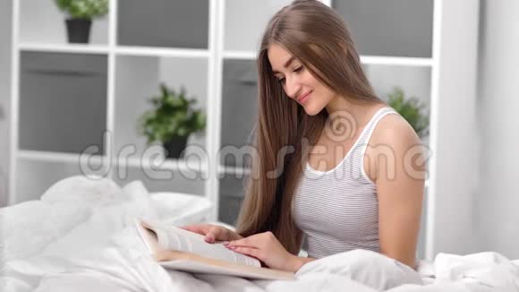 坐在床上享受休闲阅读书籍的国内美女中型摄影机视频的预览图