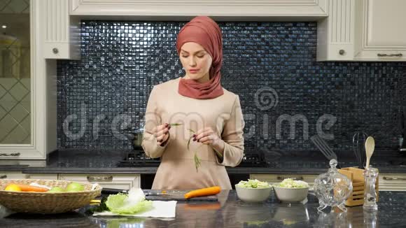东方女人站在厨房的桌子上吃青菜视频的预览图
