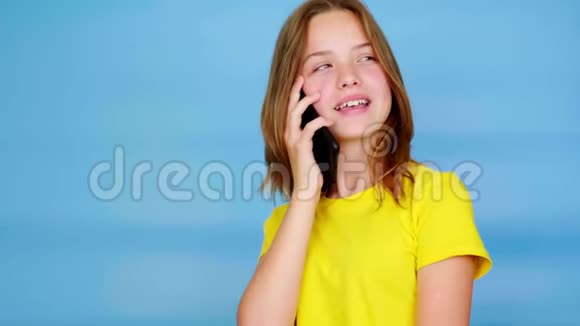 穿黄色T恤的少女正在智能手机上讲话视频的预览图