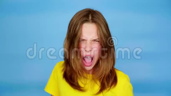 一个穿着黄色T恤的愤怒少女在尖叫看着镜头鬼脸视频的预览图