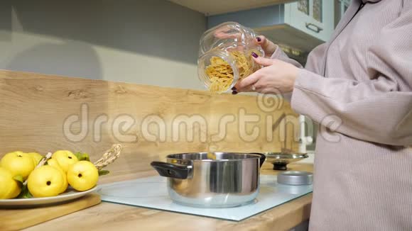 女人做晚饭把意大利面倒进炉子上的平底锅里视频的预览图