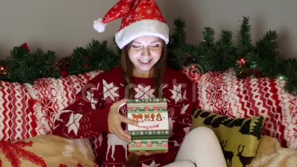 圣诞老人帽中的快乐女孩打开了一个圣诞礼物盒里面有神奇的光视频的预览图