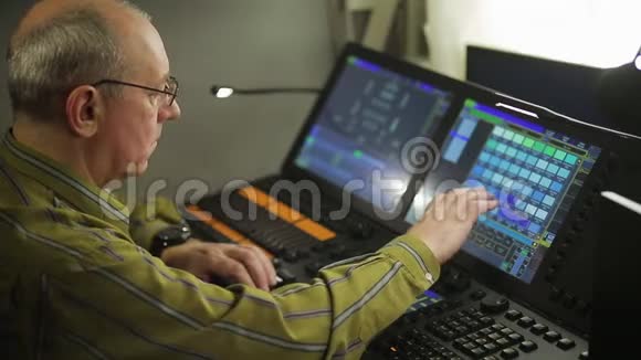 一个男性照明程序员在遥控器编程舞台灯光为一个节目视频的预览图