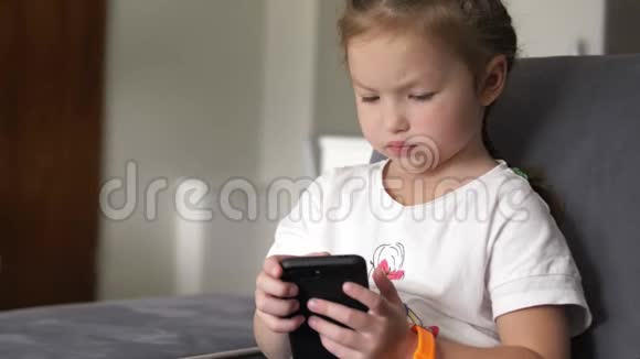 休闲儿童坐在家里的沙发上玩和触摸手机视频的预览图