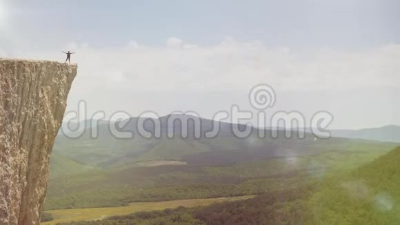 运动员征服高山的空中射击游客站在山的边缘举手向视频的预览图