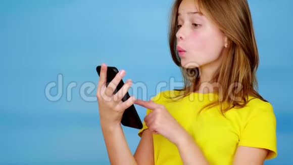 穿黄色t恤的少女在智能手机上滑动惊讶地说哇视频的预览图