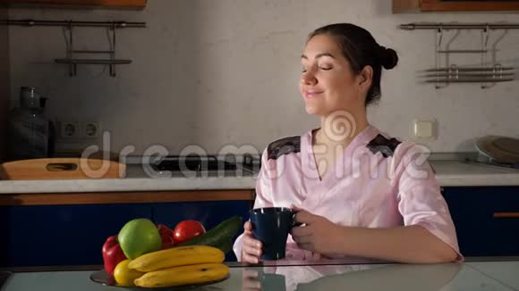 女人坐在桌子旁闻着咖啡的气味拿着杯子视频的预览图