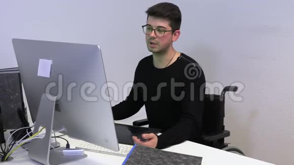 坐轮椅在电脑工作场所的年轻人视频的预览图