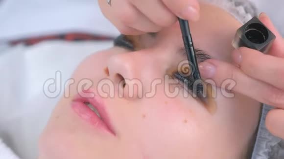 美容师正在画客户她的女人睫毛黑色面部特写视频的预览图