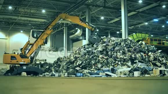 垃圾垃圾废品回收厂挖掘机正在室内垃圾场工作视频的预览图