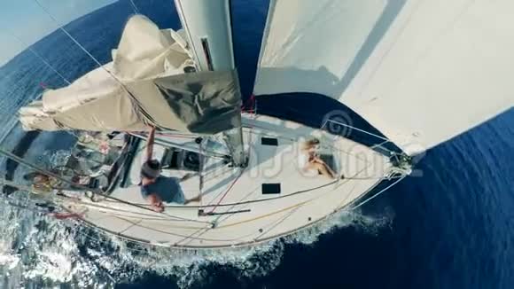 一艘白帆漂流船和船上的人的俯视图视频的预览图