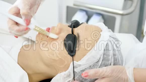治疗师在女性客户脸上涂抹特殊药膏视频的预览图
