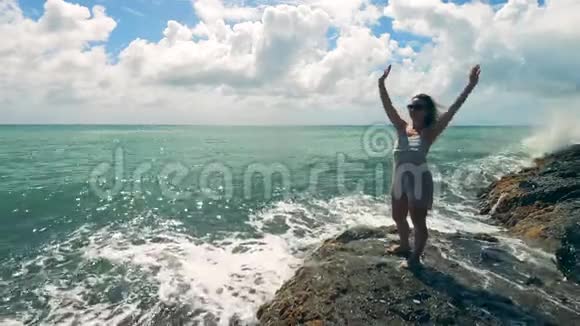 海边有一个快乐的女人站在岩石上视频的预览图