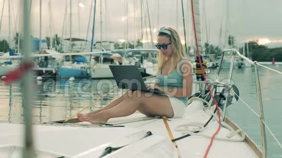 漂亮的女士在帆船上使用笔记本电脑时微笑着视频的预览图