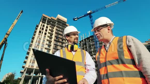 工作工程师建筑建筑师讨论施工计划使用笔记本电脑同时站在建筑工地视频的预览图