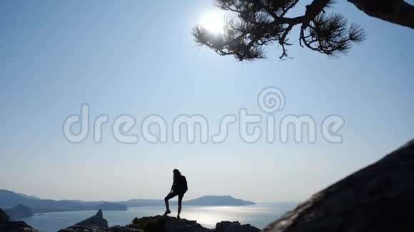 年轻的运动女孩享受大自然的美丽站在悬崖的顶端女游客背着背包站在视频的预览图