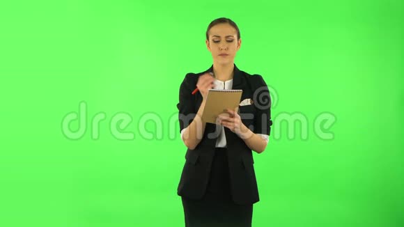 女孩站着思考然后愤怒地用铅笔在笔记本上写字绿色屏幕视频的预览图