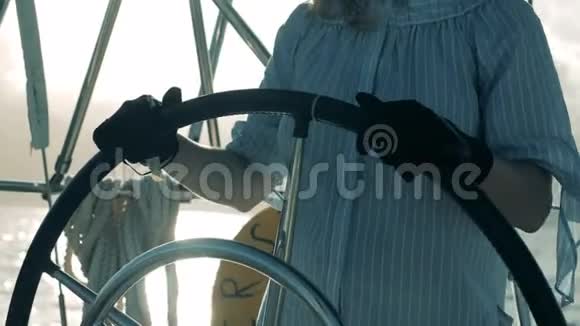 帆船船长在她的游艇上夫人戴着手套手里拿着一艘船轮子视频的预览图