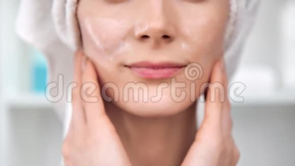女性手施白色化妆霜触摸脸4k龙红相机视频的预览图