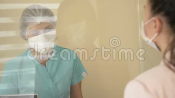 接待处的病人在医院戴防护手套和医用口罩的护士告知患者视频的预览图