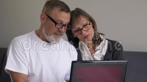 老两口笑着说着做着远距离视频通话看着坐在沙发上的笔记本电脑摄像头老成视频的预览图