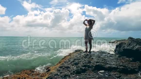 一个女人站在岩石海岸边伸展身体视频的预览图