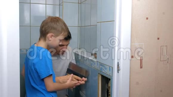 爸爸和儿子在家里一起做装修把厕所里的墙上的瓷砖去掉视频的预览图