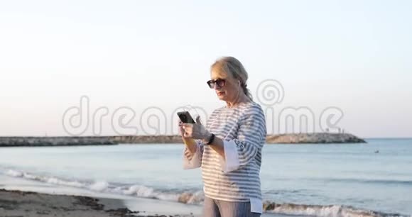 相机飞了六十岁的女人在苗条的耳机里享受音乐视频的预览图