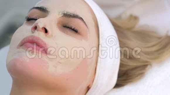 美容师戴手套从女人脸上擦拭护肤面具特写肖像视频的预览图