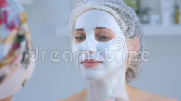 美容师正在用刷子在女人的脸上涂上面膜视频的预览图