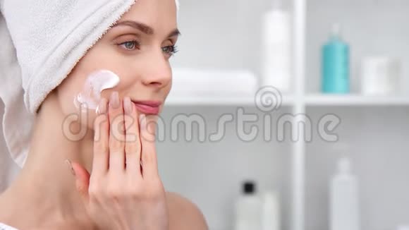 可爱的女性在脸上涂上化妆品水化霜中型近距离拍摄4k红色相机视频的预览图