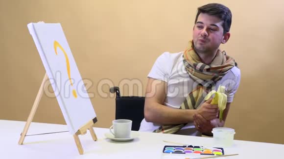 餐桌上的艺术家吃香蕉等待灵感视频的预览图