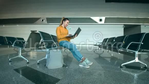 一位女士在机场用笔记本电脑打字时正在微笑视频的预览图
