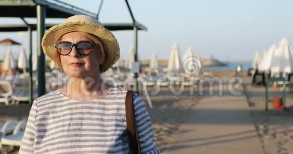 一位开朗的老年妇女在日出时一大早就从海滩上回来视频的预览图