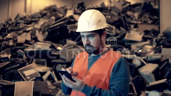 垃圾塑料回收厂一个正在操作智能手机的垃圾填埋工人视频的预览图