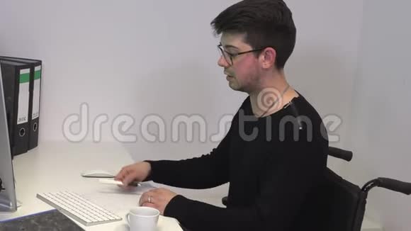办公室经理坐在轮椅上一位黑发男子在电脑附近的工作场所举行了一次在线会议视频的预览图