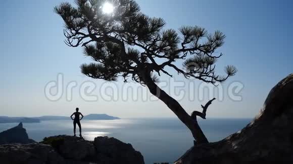 一个受启发的年轻女孩站在高高的悬崖上缓慢地向太阳挥手女人爬了一个视频的预览图