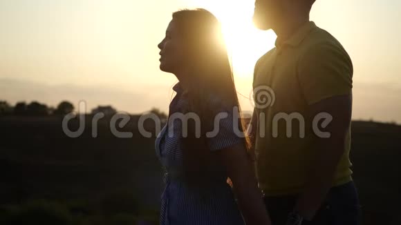 可爱的女孩穿着一件连衣裙一个男人牵着手在夕阳下的田野上缓慢地调情快乐可爱视频的预览图
