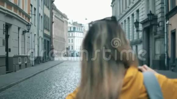一位女性游客拍摄街道建筑照片的背面视频的预览图