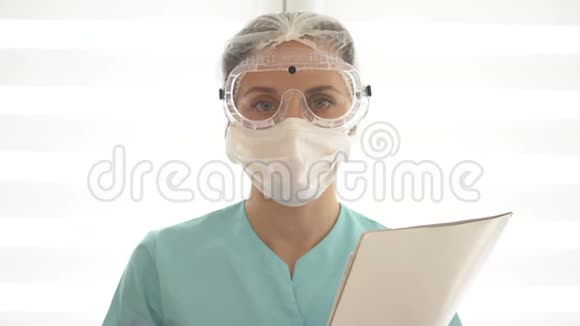 年轻护士或女医生戴着医用口罩护目镜和一次性手套她做了个警告手势视频的预览图