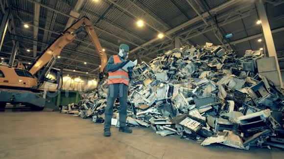 填埋工人正在观察一堆破碎的办公室机器回收行业废旧电子回收工厂视频的预览图